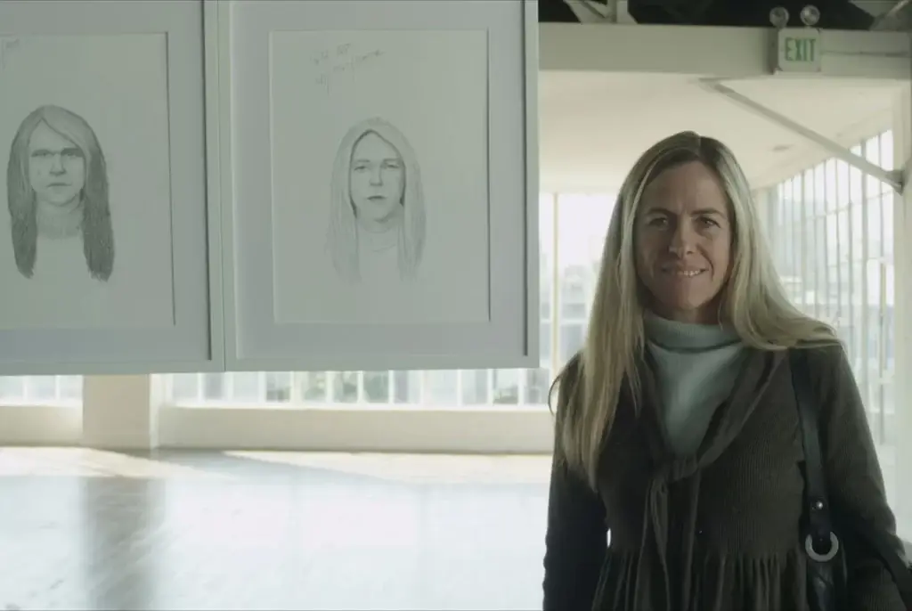 Campanha Dove Real Beauty Sketches. Fotografia de uma mulher sorridente em ambiente de galeria ou museu de arte, ao lado de desenhos de retratos feitos a carvão ou lápis exibidos na parede