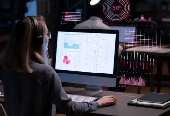 Pessoa analisando gr&aacute;ficos e dados em uma tela de computador com gr&aacute;ficos interativos, representando an&aacute;lise de dados em ambiente de trabalho moderno.
