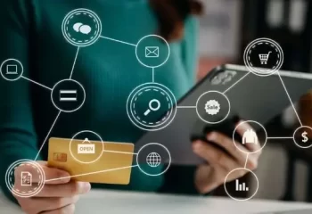 Imagem que representa atividades de compra online, mostrando uma pessoa usando um tablet e um cart&atilde;o de cr&eacute;dito com &iacute;cones de e-commerce.