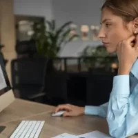 Funcionária olhando atentamente para monitor em ambiente de trabalho.