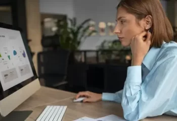 Funcion&aacute;ria olhando atentamente para monitor em ambiente de trabalho.