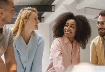 Grupo de jovens sorrindo e interagindo em um ambiente moderno.