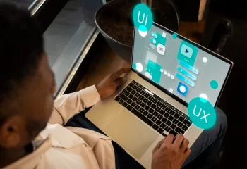 Imagem de uma pessoa utilizando um laptop com elementos gr&aacute;ficos representando design responsivo, UI e UX.