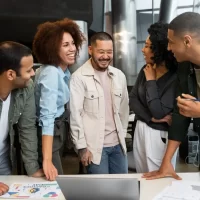 Grupo de pessoas sorrindo e conversando em ambiente corporativo, representando reconhecidos nomes do marketing digital.