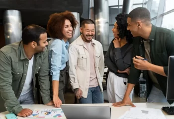Grupo de pessoas sorrindo e conversando em ambiente corporativo, representando reconhecidos nomes do marketing digital.