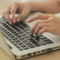 Pessoa digitando em um laptop sobre uma mesa clara, mostrando foco e produtividade no trabalho.